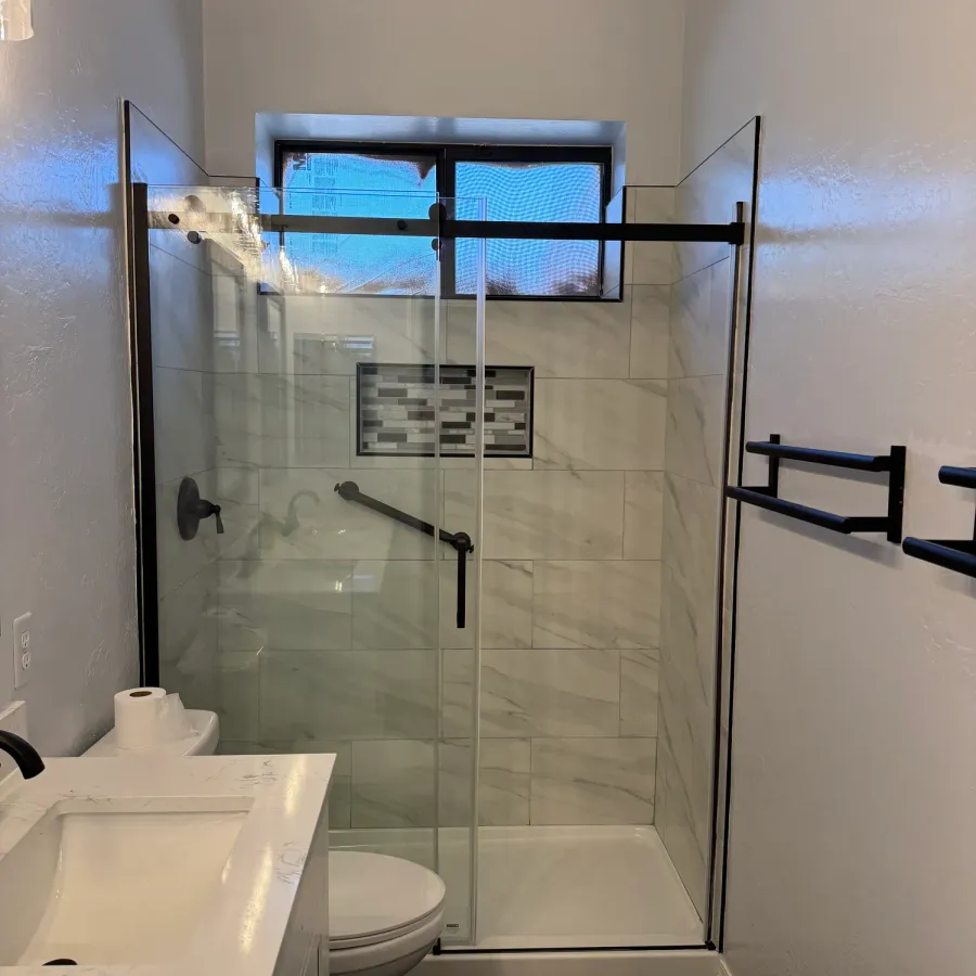 A remodeled bathroom with a glass shower and marble-look tile