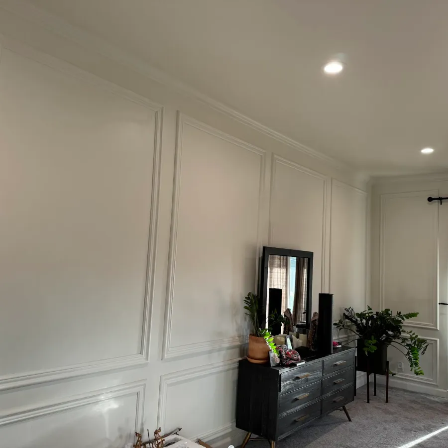 A bedroom painted white with picture-frame moulding on the walls