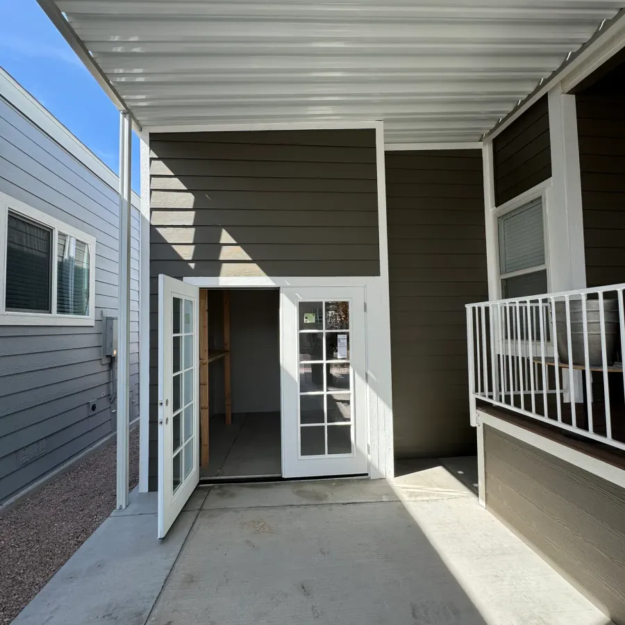 A covered patio with new grey siding and open French doors