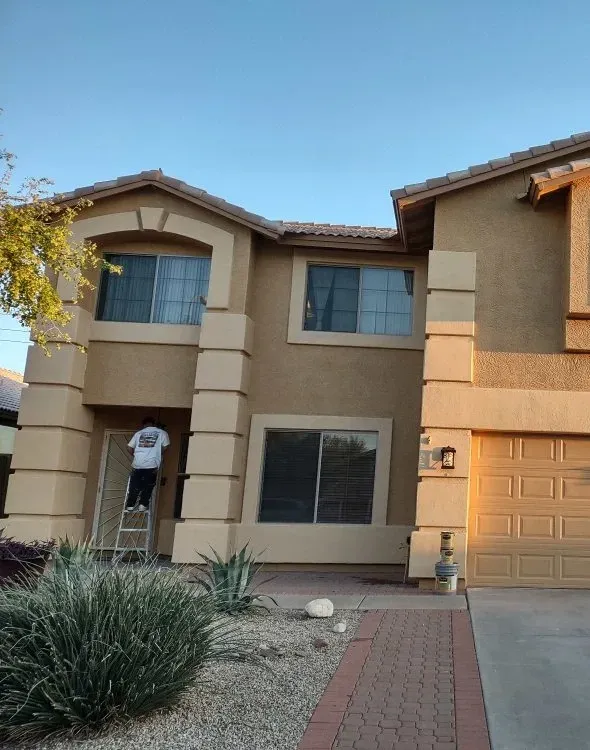 A Kodiak Paint and Construction painter repainting a two-story stucco home in the East Valley