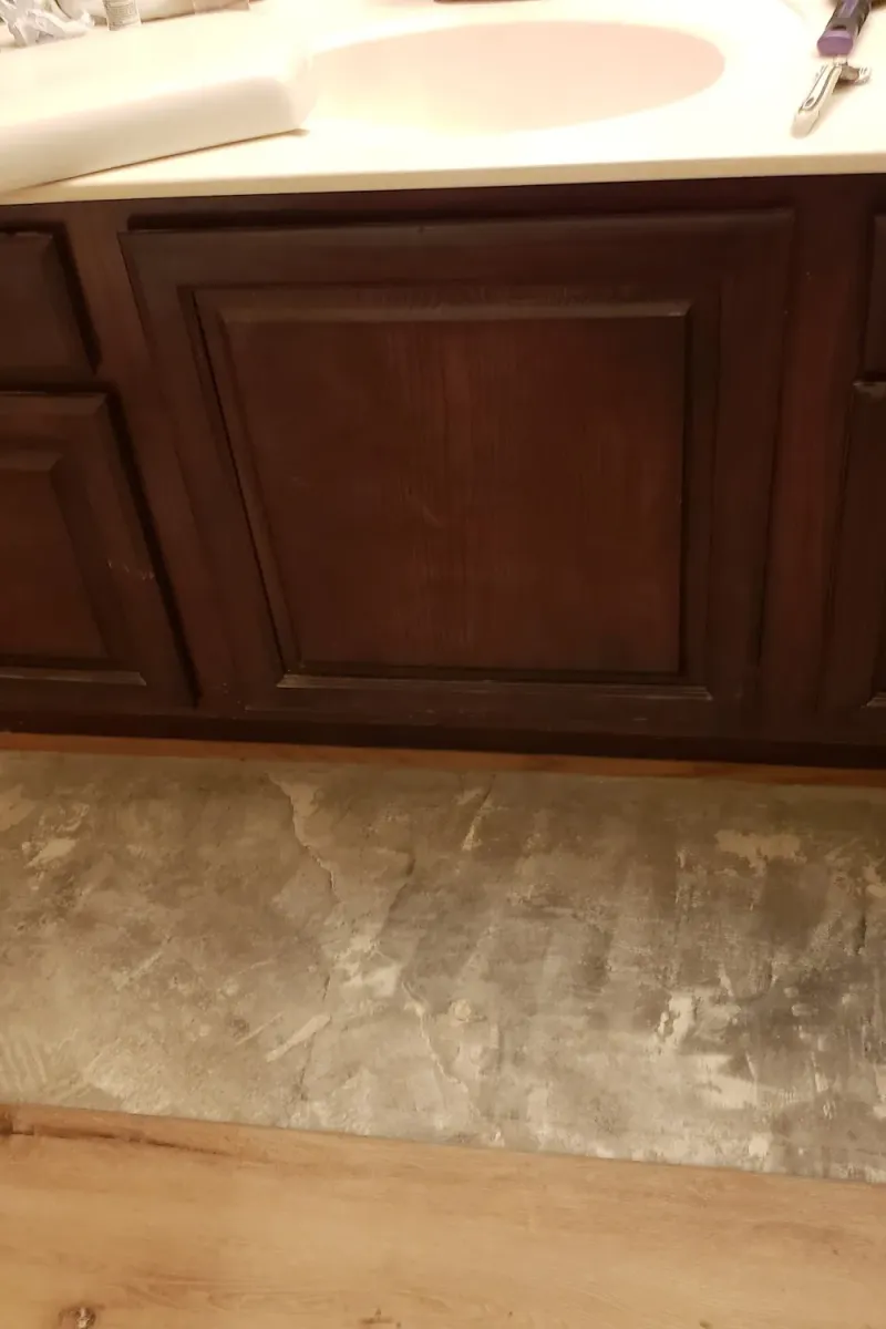 A dark wood bathroom vanity, before painting