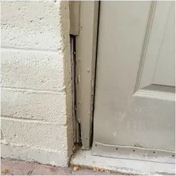 Damaged stucco and trim along a door jamb