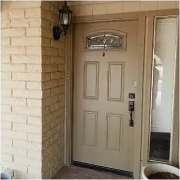 A front door and sidelight in a stucco and brick entry