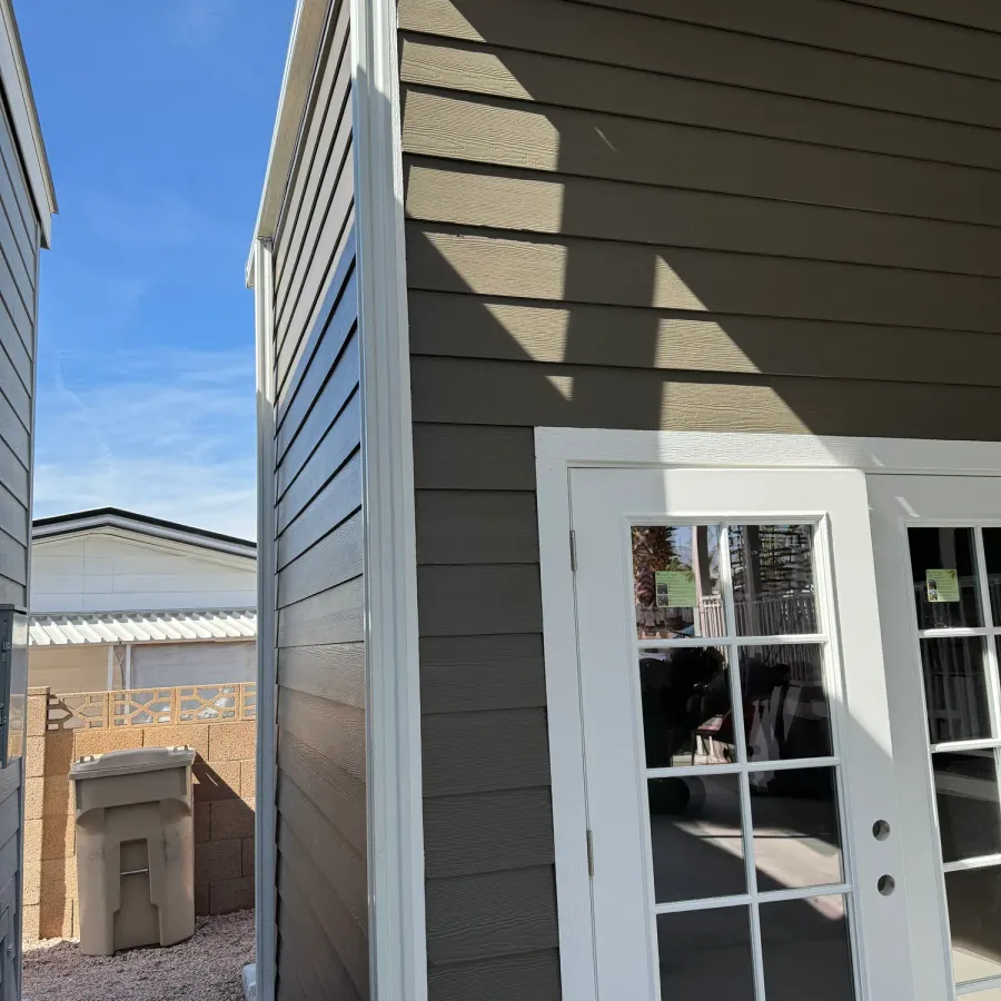 Grey lap siding and white-trimmed French doors on the side of a home