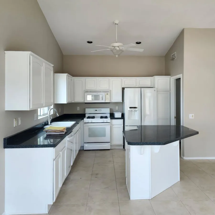A kitchen with cabinets painted white and a dark granite island