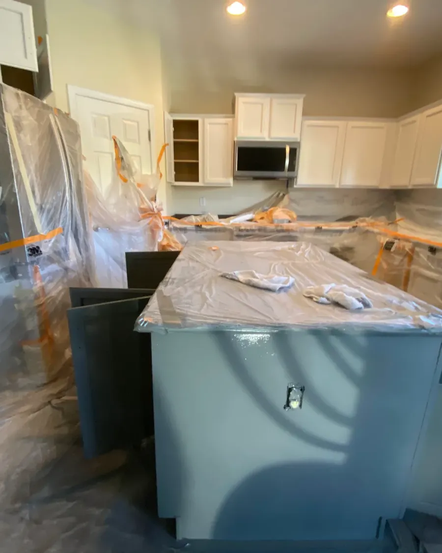 A kitchen fully masked in plastic sheeting before its cabinets are painted