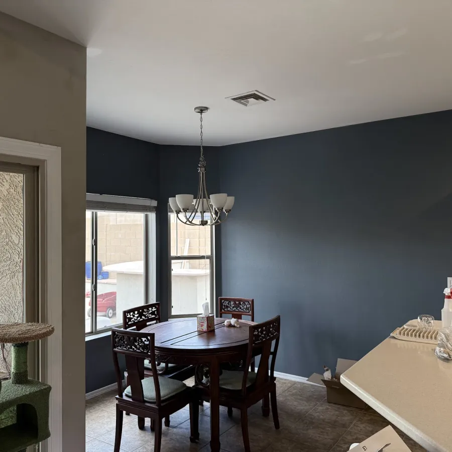 A dining room with navy painted walls and a chandelier