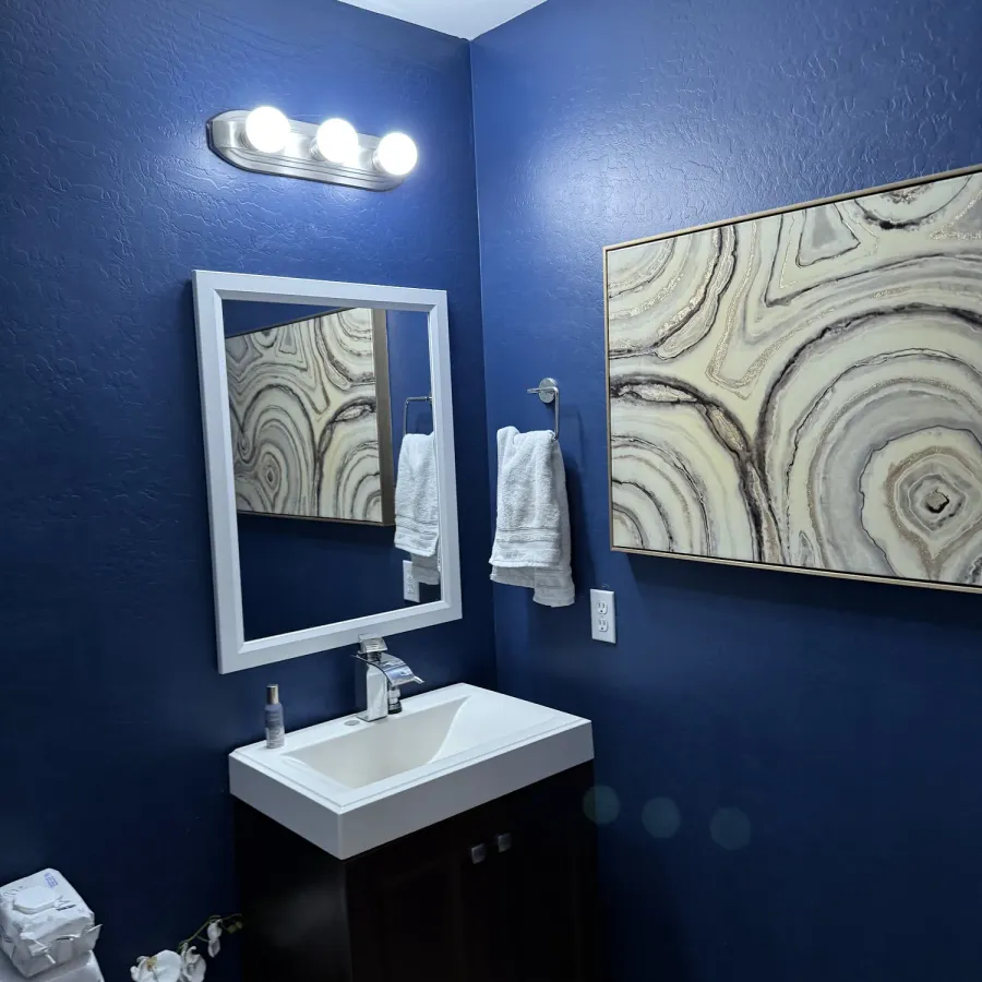 A small bathroom painted navy blue with a white vanity