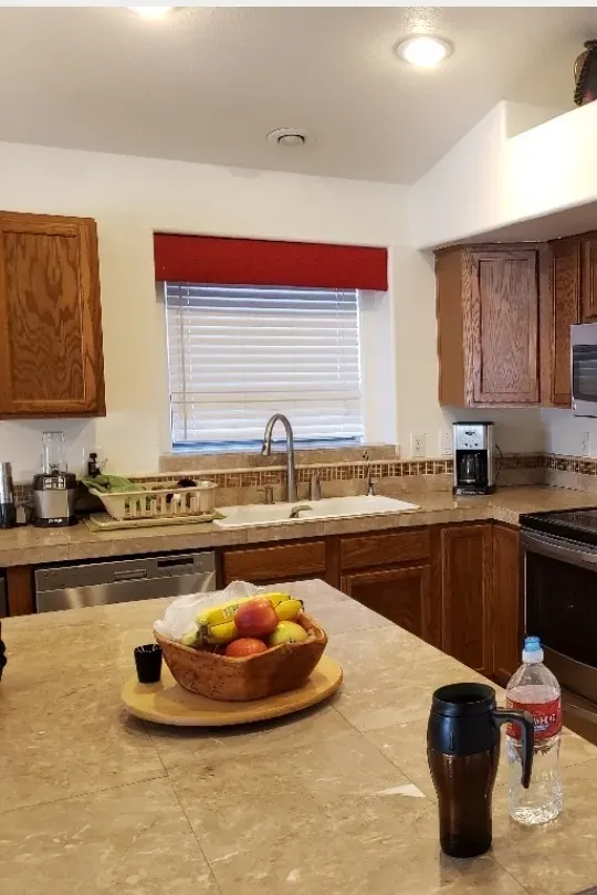 Oak kitchen cabinets around a window and fridge, before painting