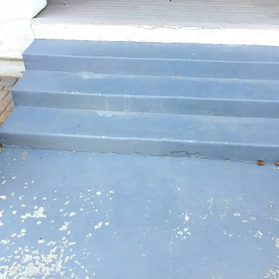 Gray paint flaking off a concrete patio slab beside painted steps