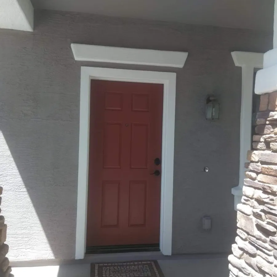 A red front door with white trim between stone pillars
