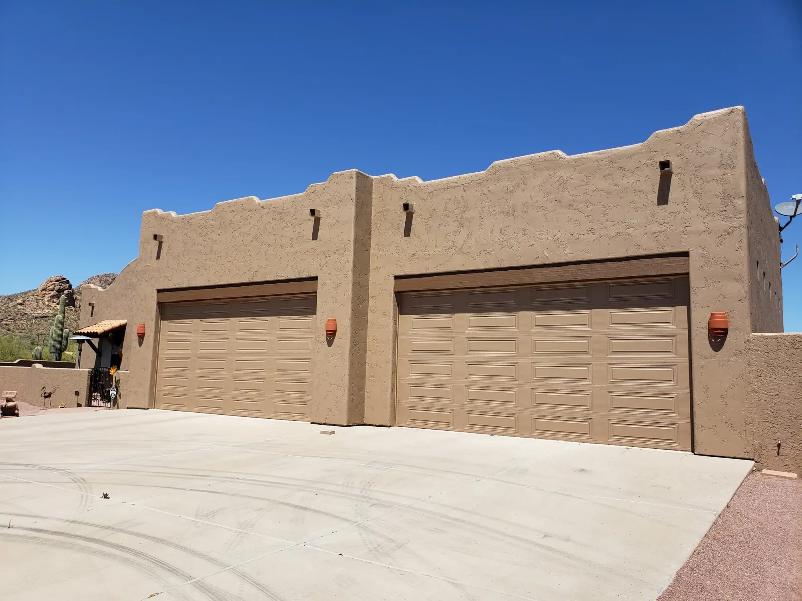 A Santa Fe–style stucco home with two garage doors, freshly painted