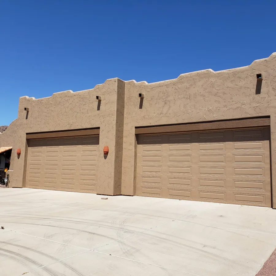 A Santa Fe–style stucco home with two garage doors, freshly painted