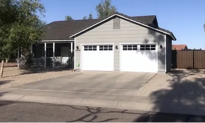 The same home in grey with white garage doors and a dark roof