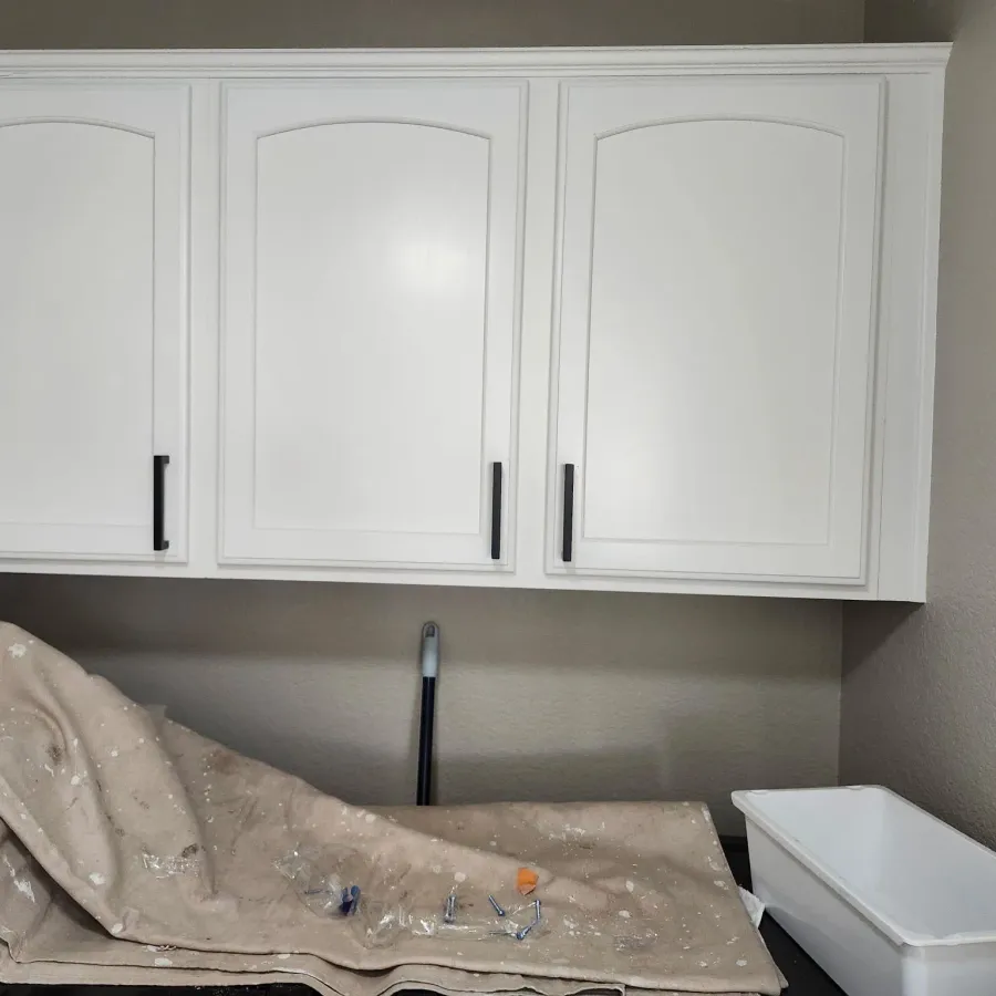 Upper kitchen cabinets painted white, with drop cloths on the counter below