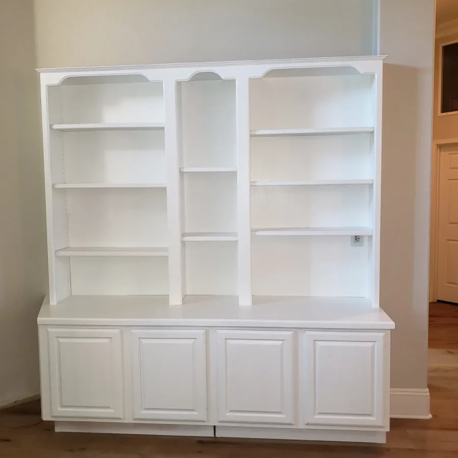 A built-in bookcase and cabinet unit painted white