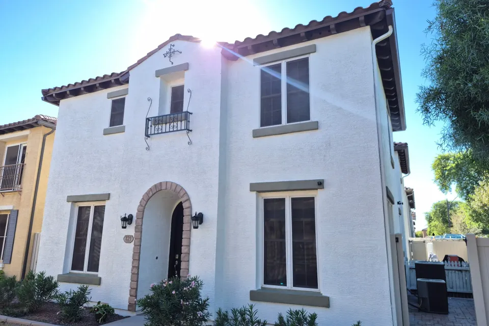 A two-story white stucco house with an arched entry