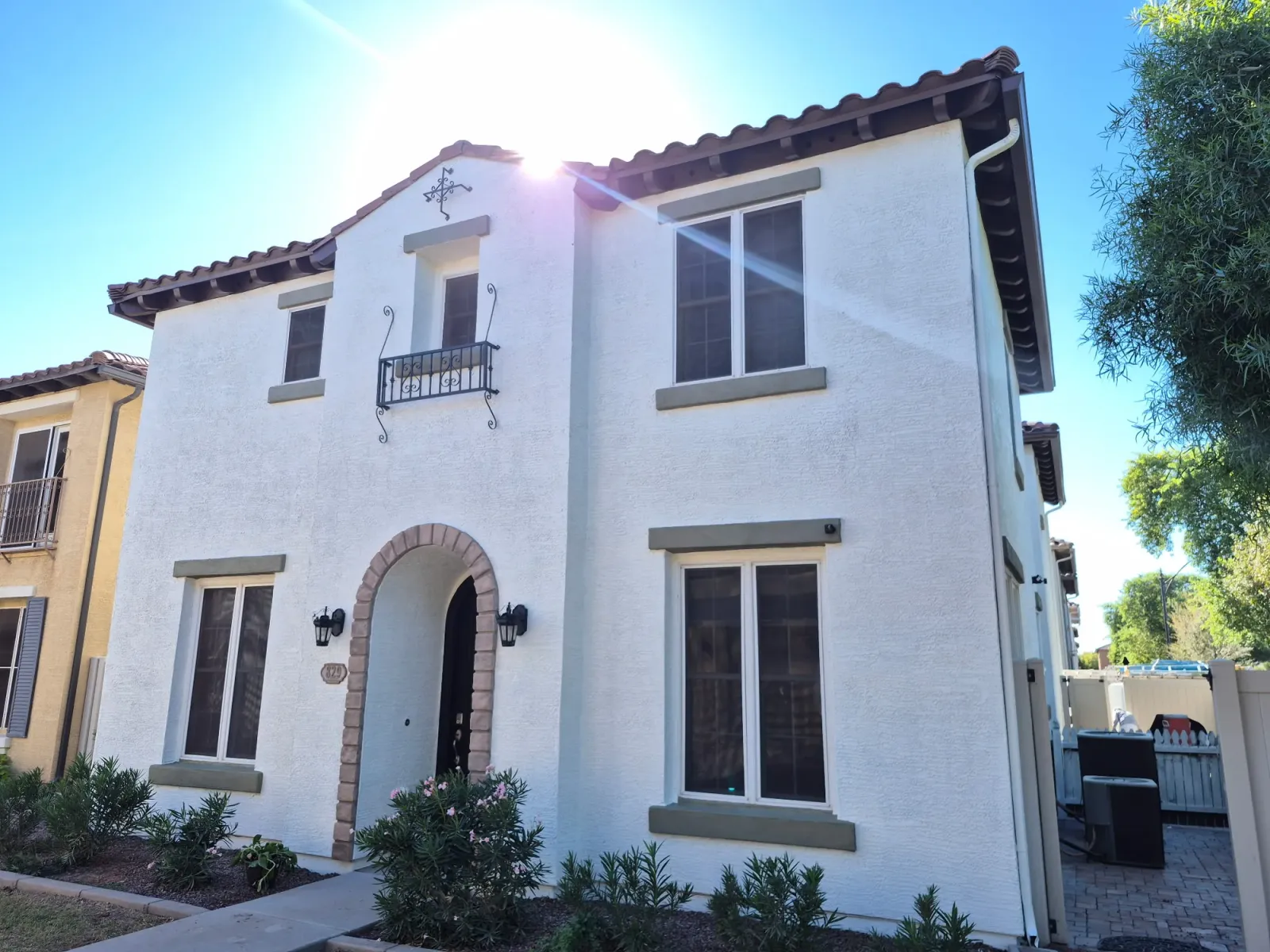 A two-story white stucco house with an arched entry