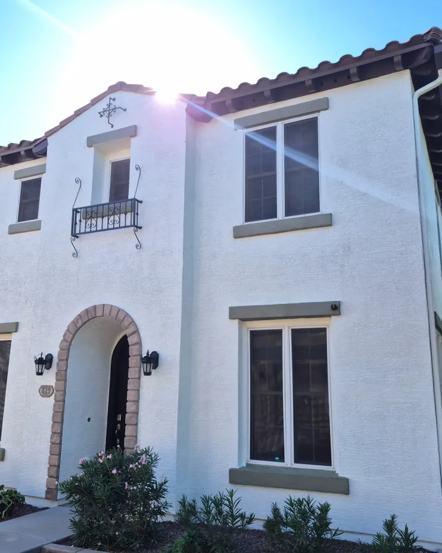 A two-story white stucco house with an arched entry