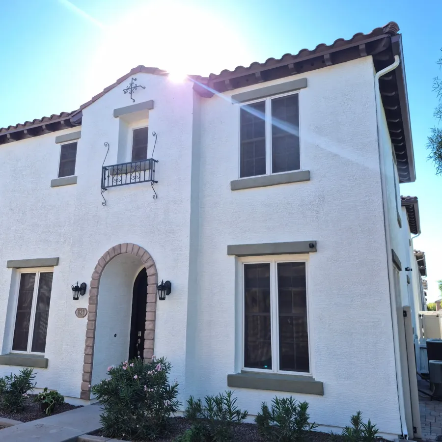 A two-story white stucco house with an arched entry