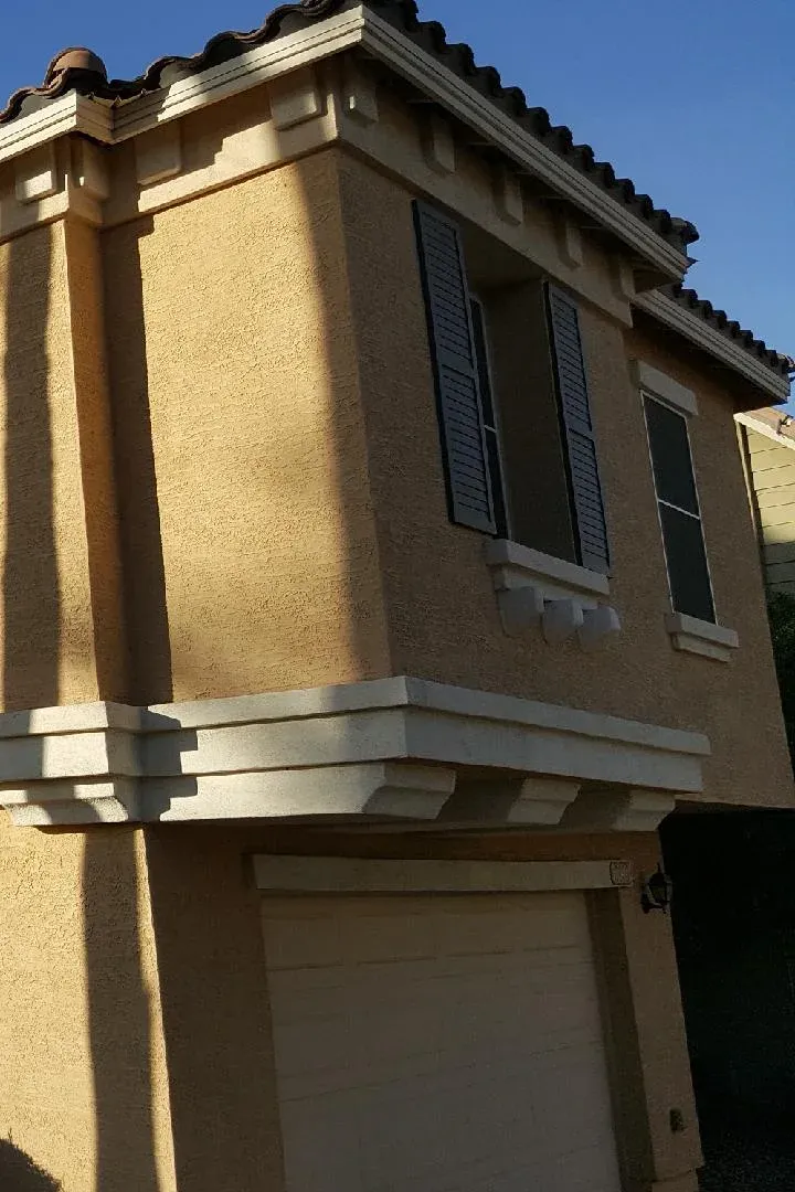 A two-story stucco house painted yellow, before the repaint